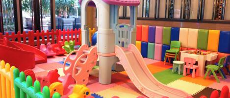 A children's play area with a slide, climbing structures, and colorful seating.