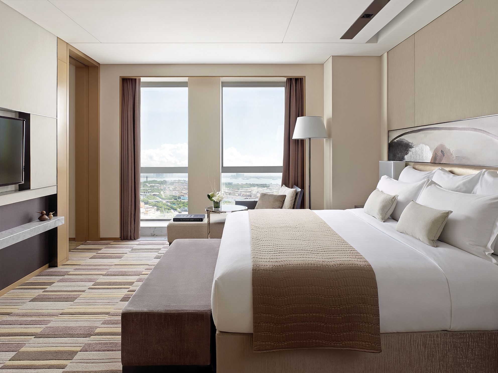 Una habitación de hotel moderna con una cama grande, televisión y vistas a la ciudad.