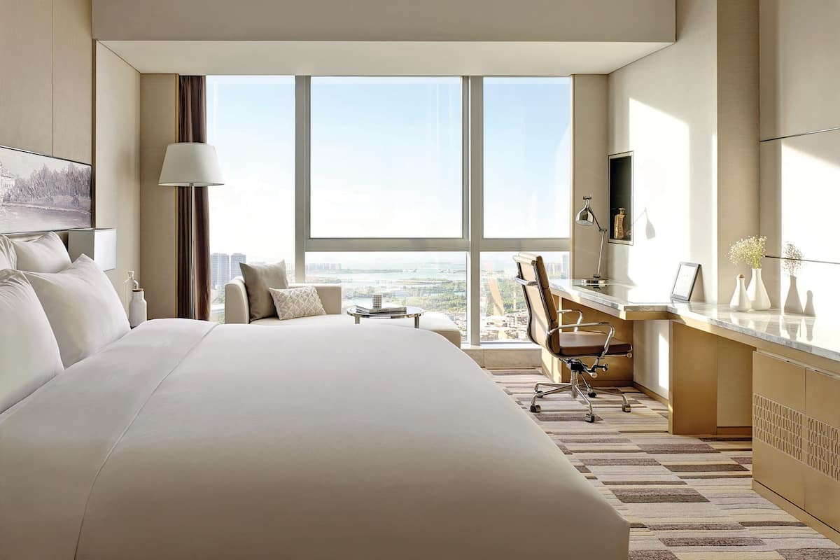 Une chambre d’hôtel moderne, dotée d’un grand lit, d’un bureau et offrant une vue sur la ville.