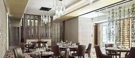 Un vaste espace dédié à la salle à manger, comprenant plusieurs tables et chaises, des luminaires modernes et des panneaux décoratifs muraux.