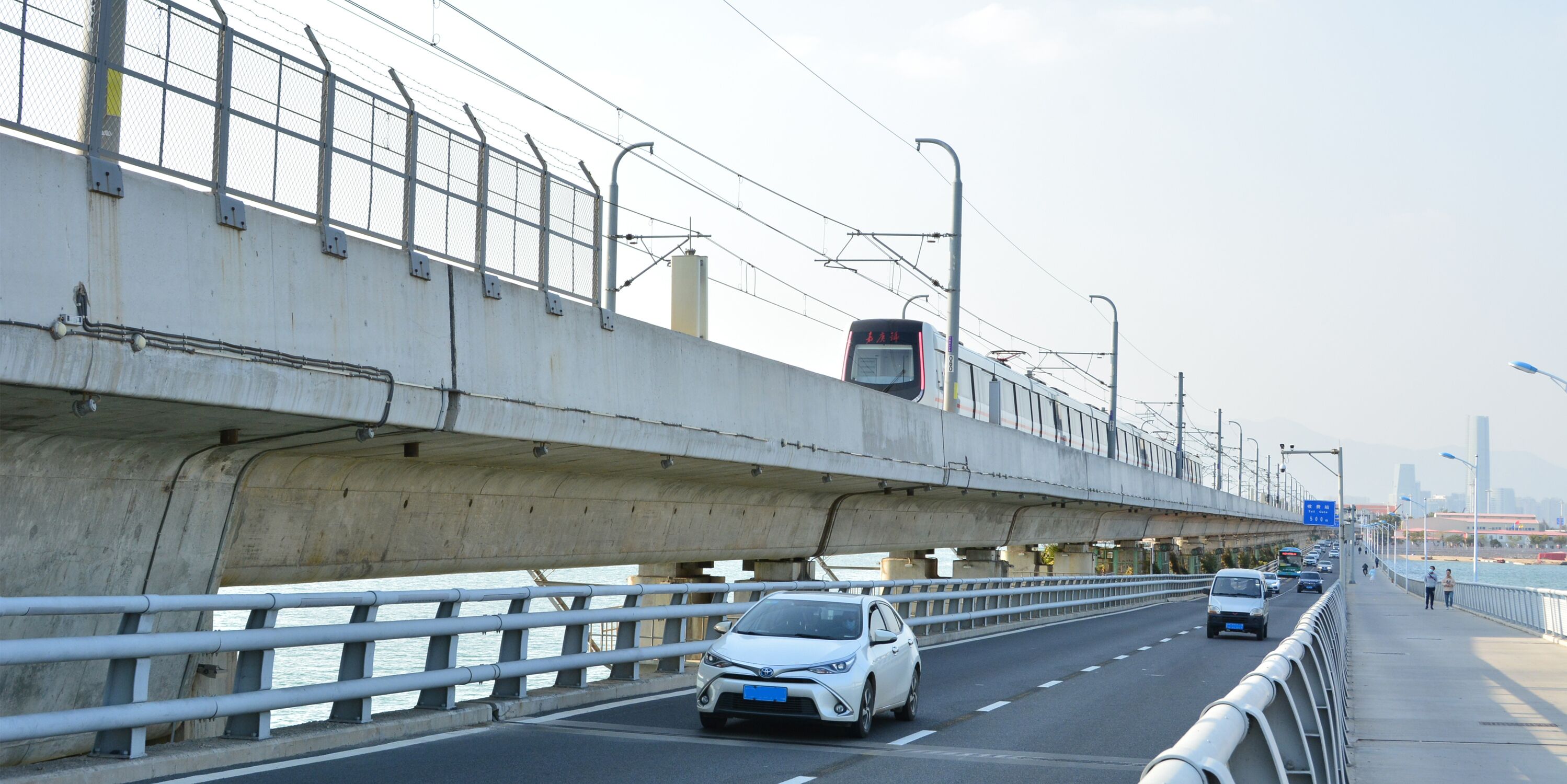 Een snelweg met meerdere rijstroken, een voetpad en een brug met een metalen hekwerk.