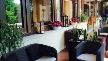 A spacious indoor area with wicker furniture, large windows, and potted plants.