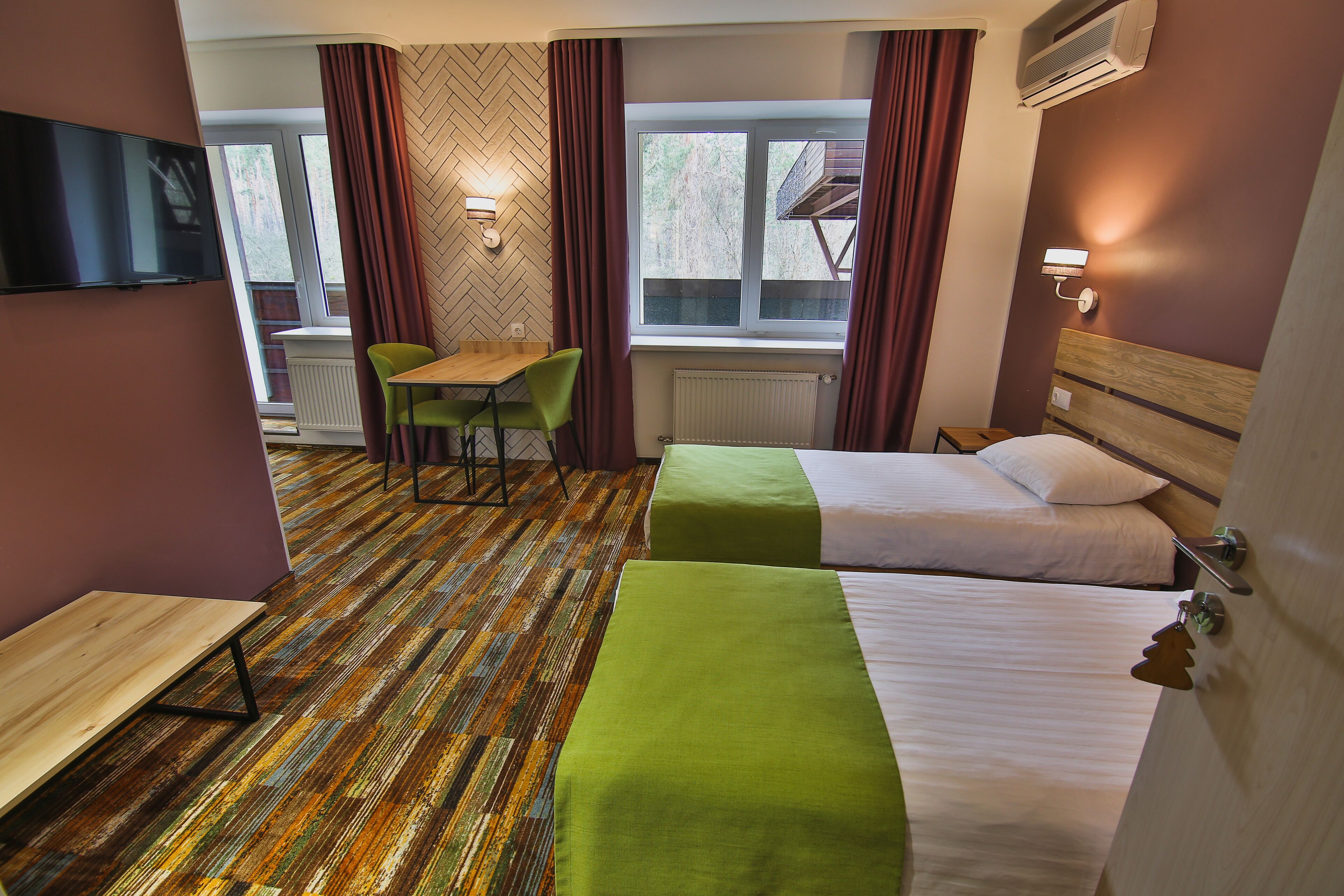 Habitación de hotel con dos camas, un escritorio, una silla y un televisor.