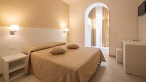 A bedroom with a bed, bedside tables, a desk, and a TV. - Hotel Falcone (Vieste)