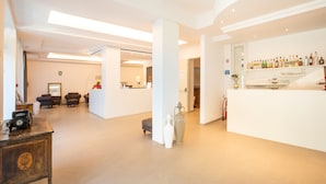 A spacious lobby with a reception desk, seating area, and a display of various items. - Hotel Falcone (Vieste)