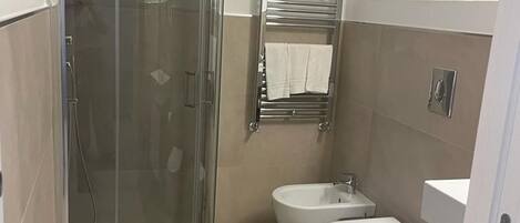 A modern bathroom with a glass-enclosed shower, a white toilet, and a bidet.