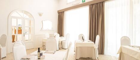 A hotel room with a large window, a mirror, a desk, and a chair.