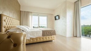 A spacious bedroom with a large bed, a television mounted on the wall, and a view of the outdoors through a large window. - Hotel Ca' Di Valle (Cavallino-Treporti)