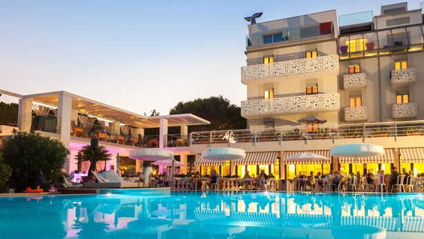 A hotel with a pool, outdoor seating, and a covered area with tables and chairs. - Hotel Ca' Di Valle (Cavallino-Treporti)