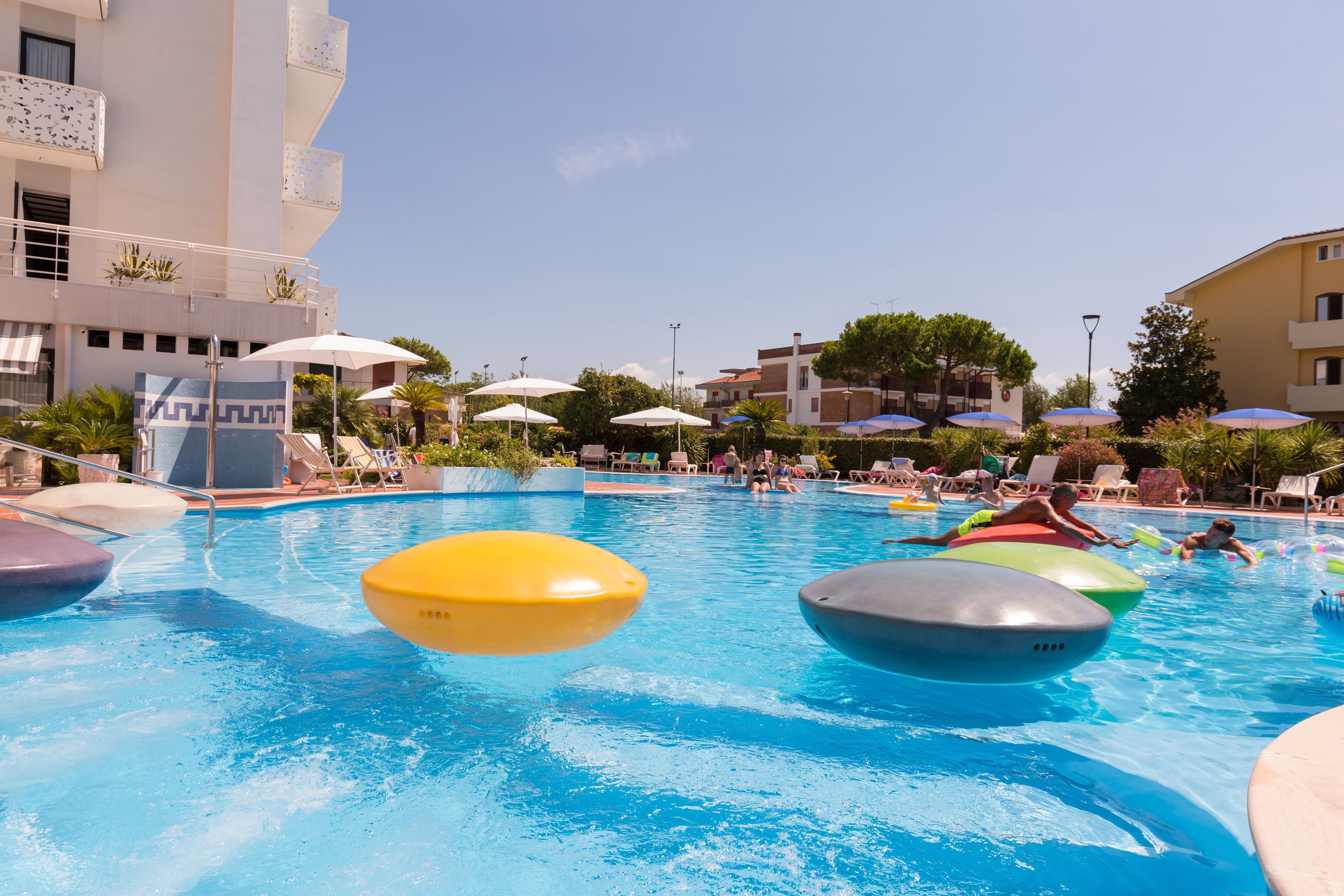 Une piscine avec des bouées colorées, des chaises longues et des parasols.