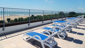 A rooftop terrace with blue cushioned chairs and a view of the beach. - Centro Vacanze Cavallino Opera Nascimbeni (Cavallino-Treporti)
