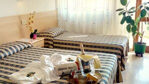 A hotel room with two beds, a nightstand, a potted plant, and a breakfast tray with a bottle of champagne and a box of chocolates. - Centro Vacanze Cavallino Opera Nascimbeni (Cavallino-Treporti)