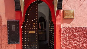 A red building with a tiled roof and a large, ornate black door with golden studs. - Ryad Amiran & Spa (Marrakech)