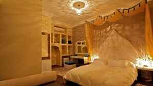A bedroom with a canopy bed, built-in shelving, and a decorative ceiling light. - Ryad Amiran & Spa (Marrakech)