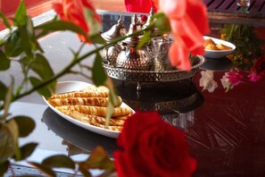 Un tavolo con un piatto di waffle, una teiera e una tazza, circondato da rose rosse.