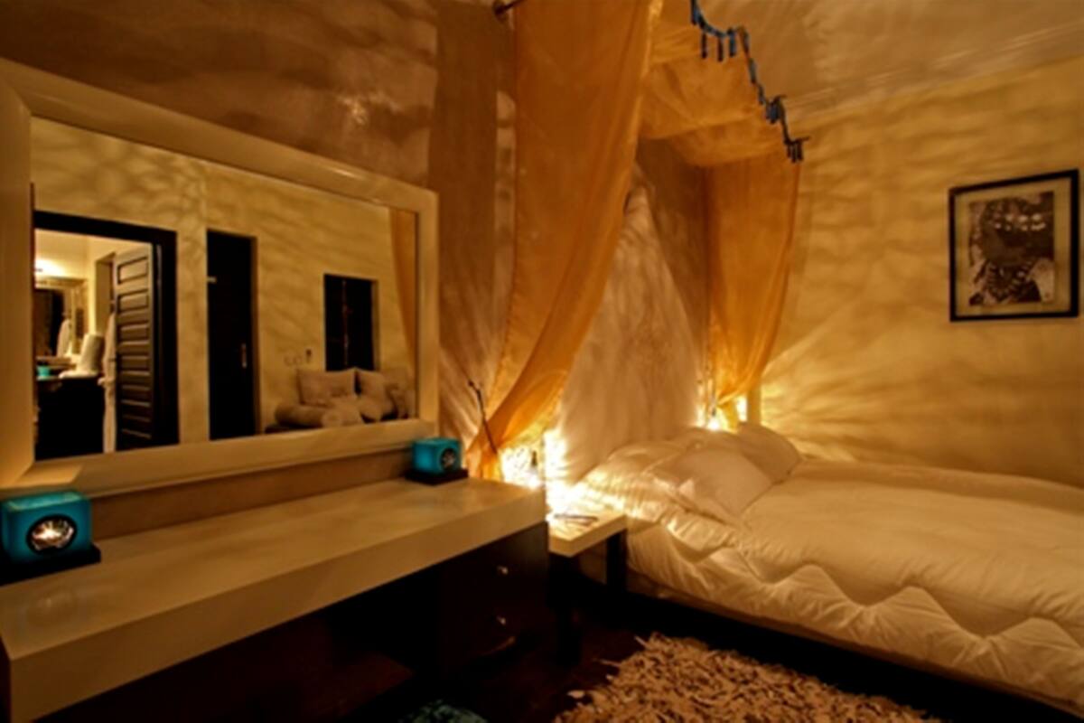 A bedroom with a large bed, a bedside table, a mirror, and a canopy.
