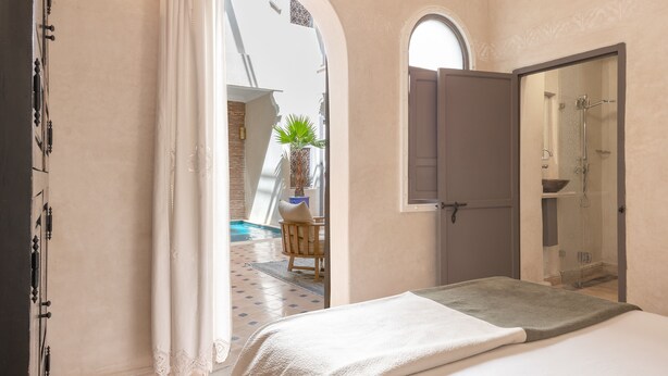 Un dormitorio con cama, ducha y vistas a una piscina y zona de estar exterior.