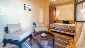 Una habitación acogedora con sofá, sillón, mesa de centro y cama con ropa de cama estampada.
