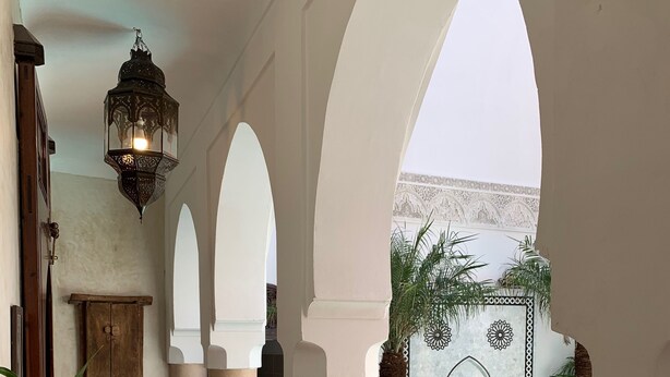 A pool area with tiled flooring, columns, and arches. - Riad Abaka by Ghali (Marrakech)