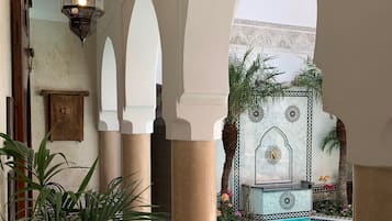Un área de piscina con suelo de baldosas, columnas y arcos.