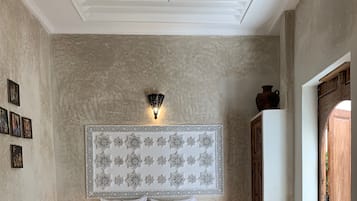 Un dormitorio con una cama grande, dos mesitas de noche con lámparas, un panel decorativo en la pared y una puerta de madera.