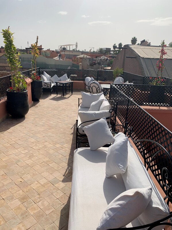 A rooftop terrace with outdoor seating, potted plants, and a view of the cityscape. - Riad Abaka by Ghali (Marrakech)