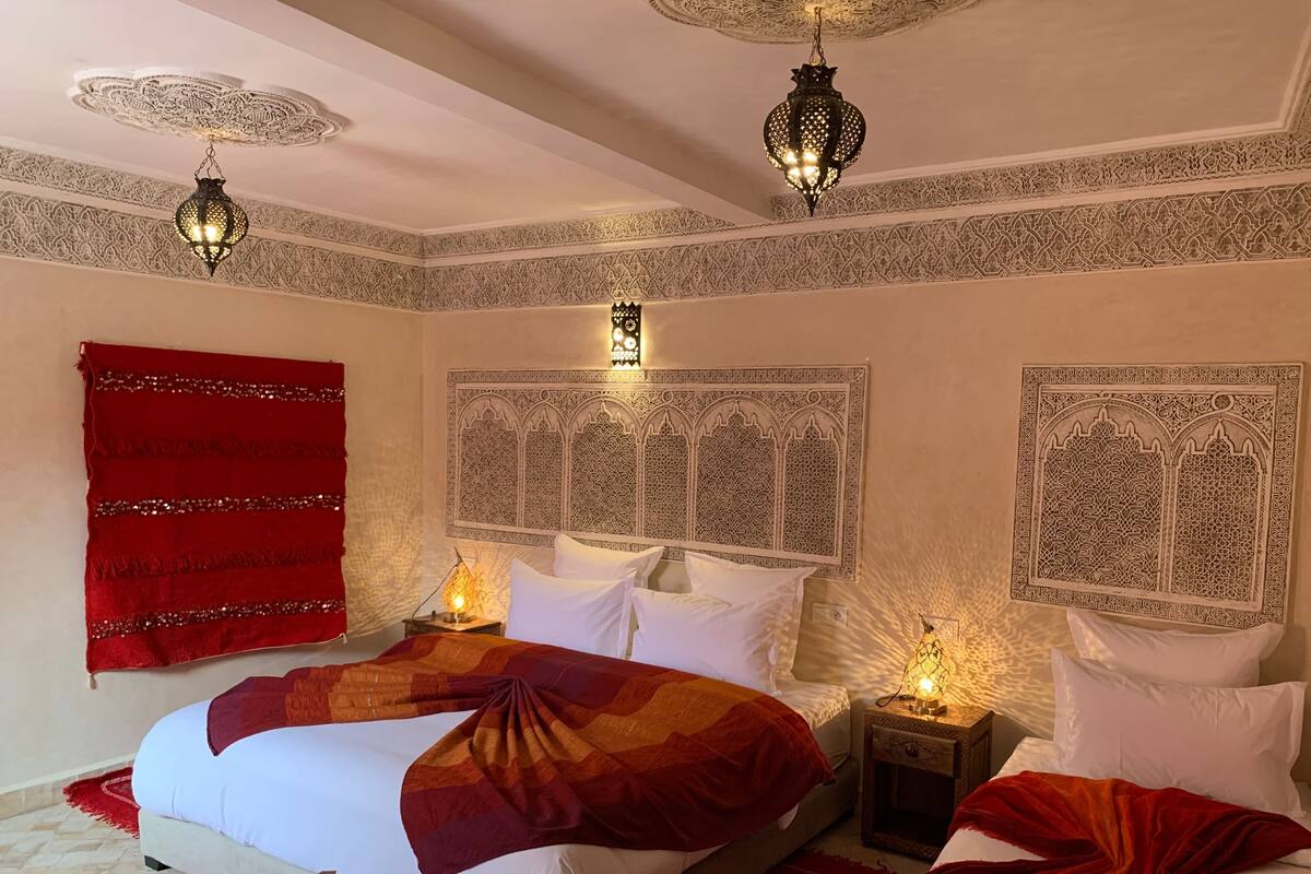 A bedroom with a large bed, decorative headboard, and intricate wall patterns.