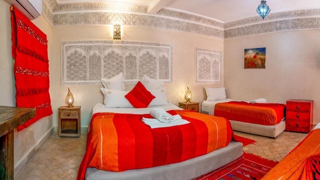 A bedroom with a large bed, a smaller bed, and a nightstand with a lamp.