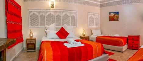 A bedroom with a large bed, a smaller bed, and a nightstand with a lamp.