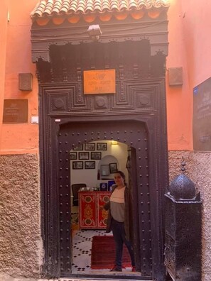 A traditional Moroccan door with intricate carvings and a sign above it. - Riad Abaka by Ghali (Marrakech)