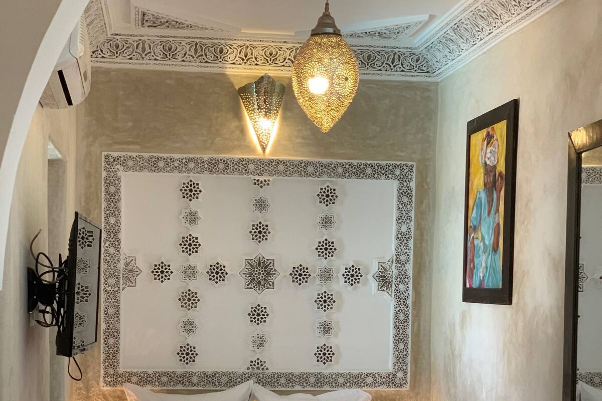 A hotel room with a bed, decorative wall panels, and a painting.