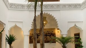 A spacious interior with high ceilings, ornate white arches, and a central painting depicting a historical scene. - Riad Abaka by Ghali (Marrakech)