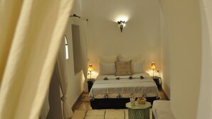 A cozy bedroom with a bed, bedside lamps, and a hanging light fixture. - Riad Sin (Marrakech)