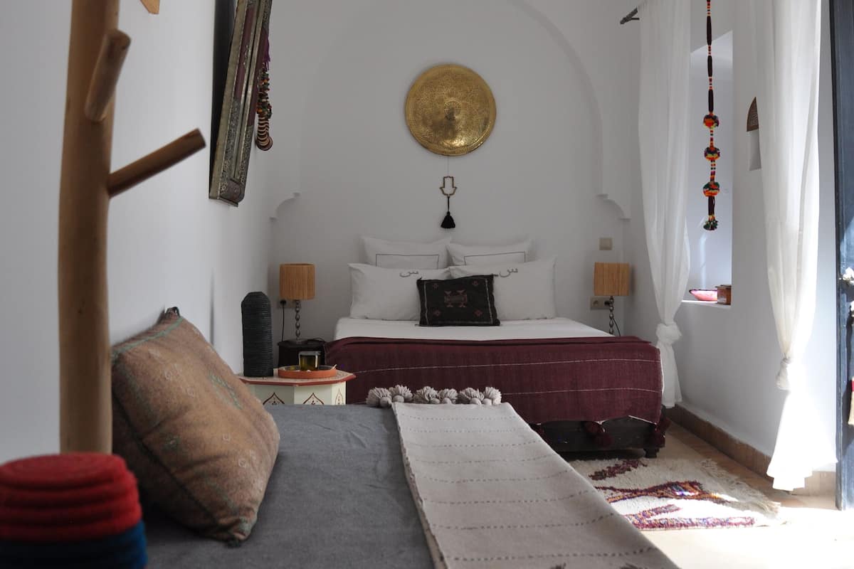 Un dormitorio con cama, mesitas de noche, lámpara colgante y un adorno en la pared.