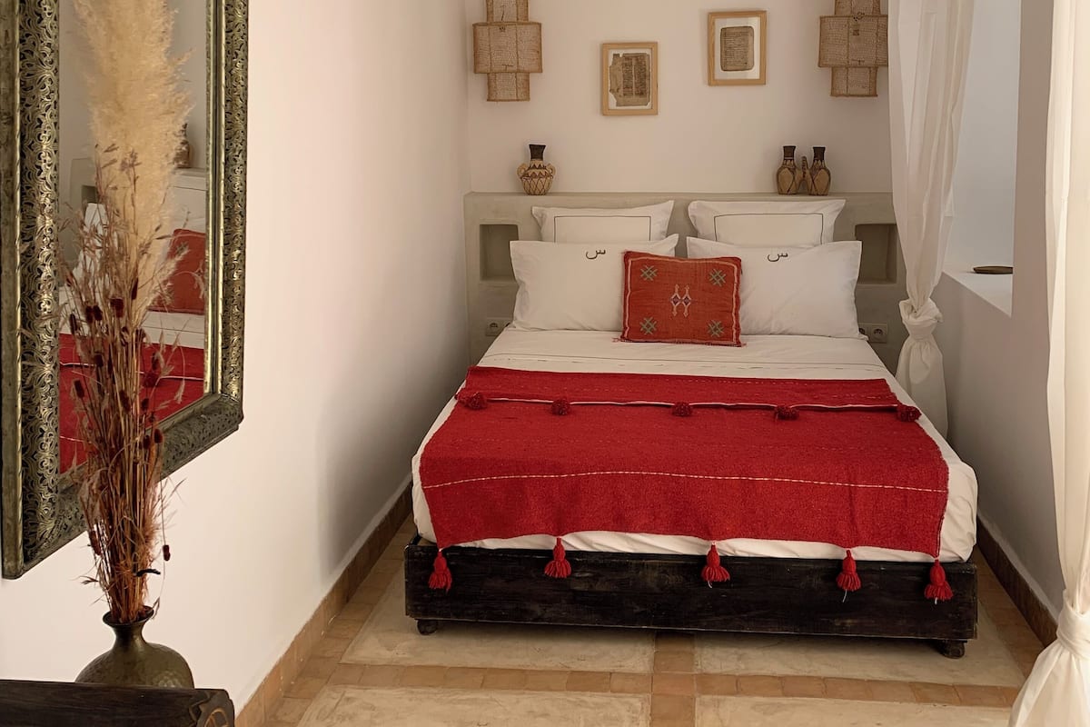 Un dormitorio con una cama, un espejo y adornos en las paredes.