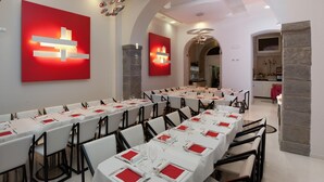 A dining area with long tables set for multiple guests, featuring white tablecloths and red napkins. - Hotel Coppe (Trieste)
