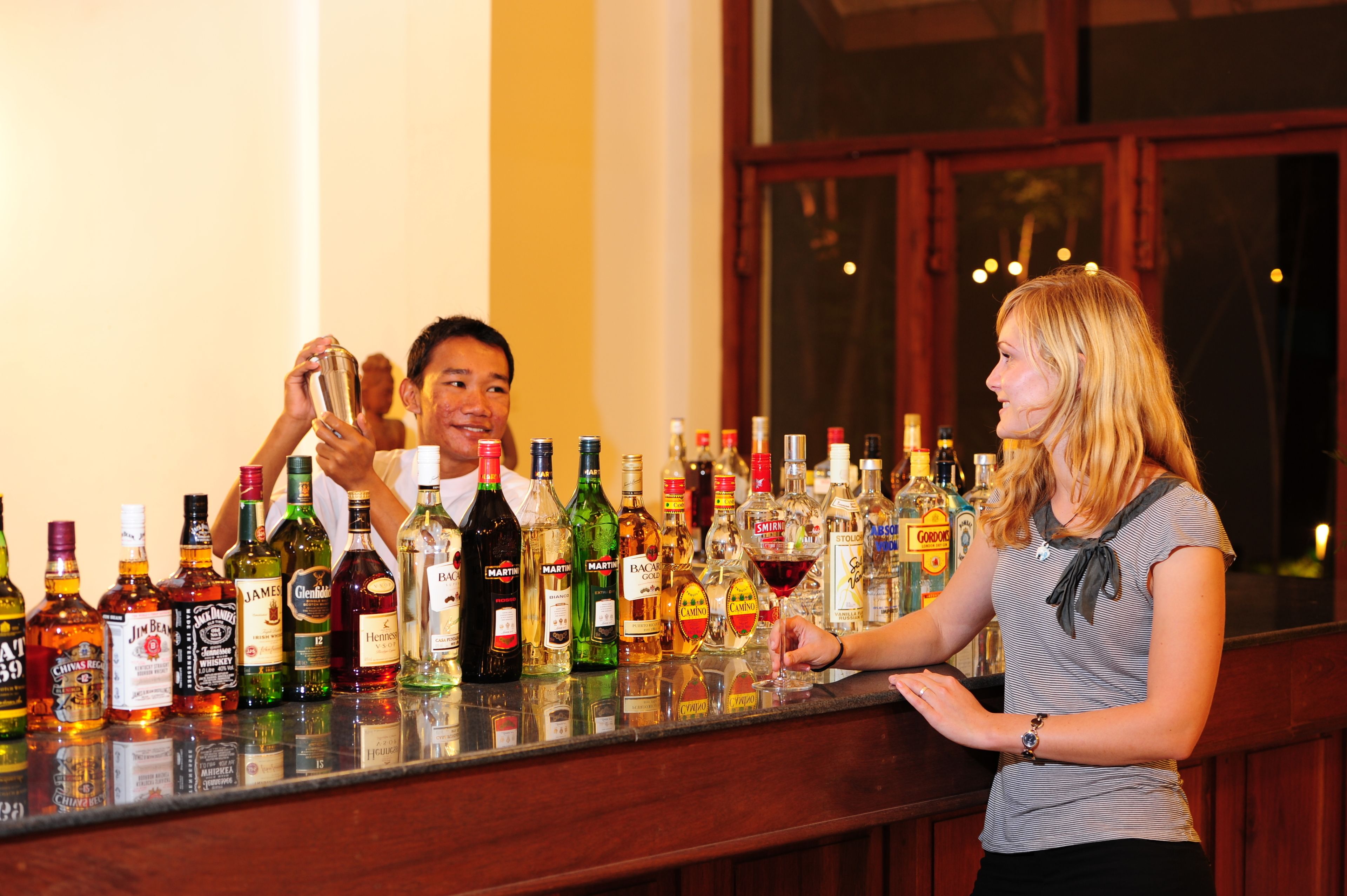 A bar with a variety of liquor bottles and a person serving.