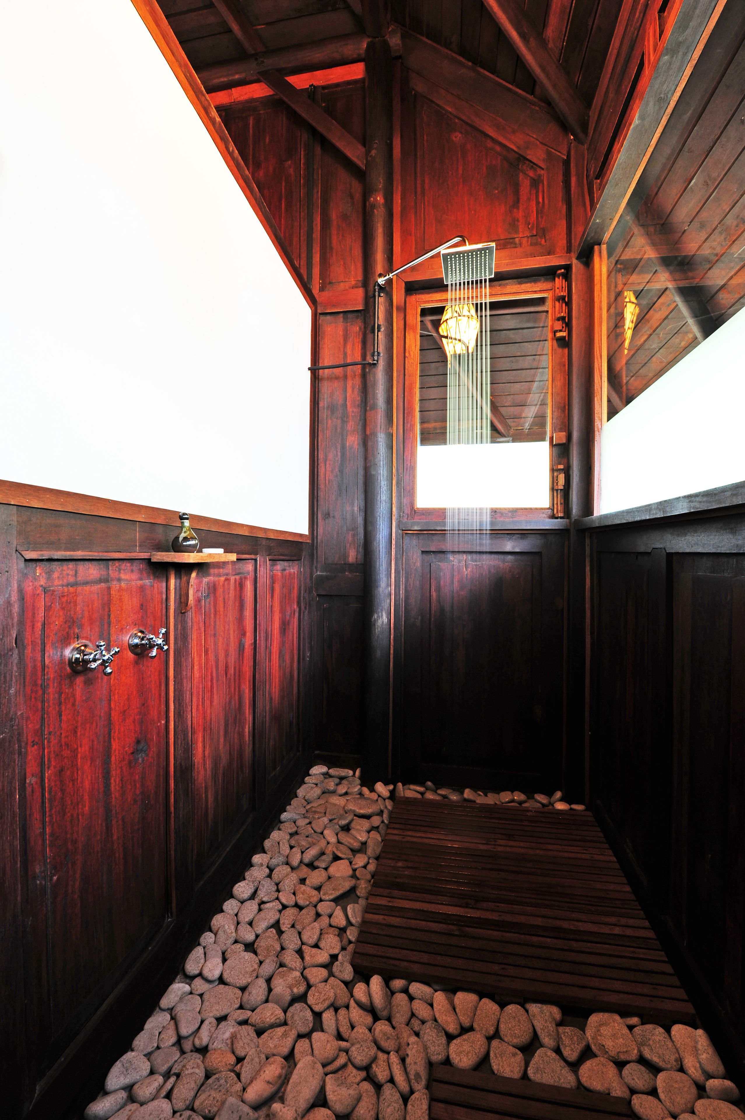 Un interior de madera con piso de madera, una ventana y una lámpara colgante.