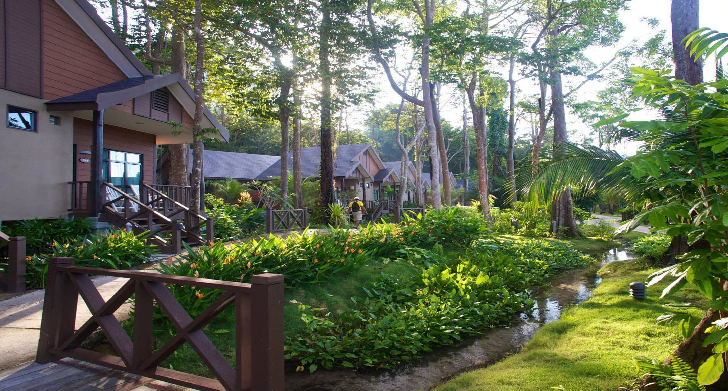A resort with multiple wooden cabins, a central pathway, and lush greenery.