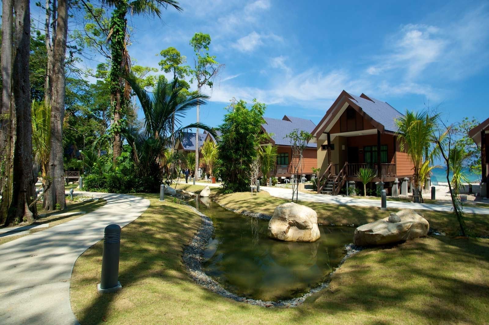 Um resort com piscina, palmeiras e vista para o oceano.