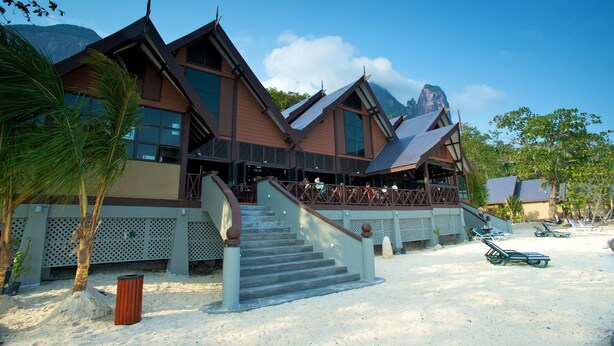 Resort com escadaria que leva a uma área coberta, praia de areia e montanhas ao fundo.
