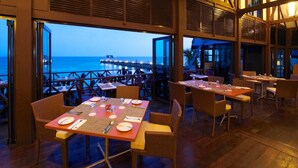 Un restaurante con mesas dispuestas para comer, con vistas a un muelle y al mar.