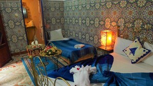 Une chambre avec deux lits, une table de chevet, une lampe et un miroir décoratif.