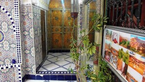 Une pièce ornée de motifs complexes en carreaux, agrémentée d’une lanterne suspendue et d’un collage d’images encadrées sur le mur.