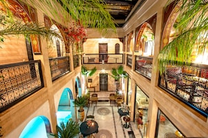 A multi-level atrium with ornate iron railings, potted plants, and a central seating area.