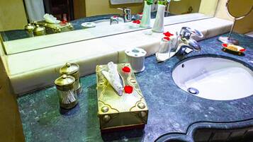 Casa de banho com um espelho grande, uma pia e produtos de higiene no balcão.