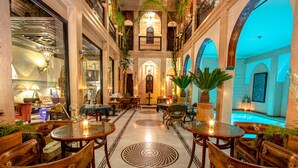 A luxurious indoor setting with ornate wooden furniture, a central fountain, and a patterned floor.