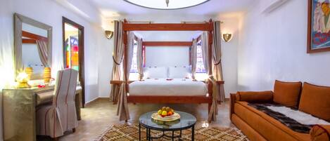 A room with a bed, a sofa, a desk, and a chandelier.