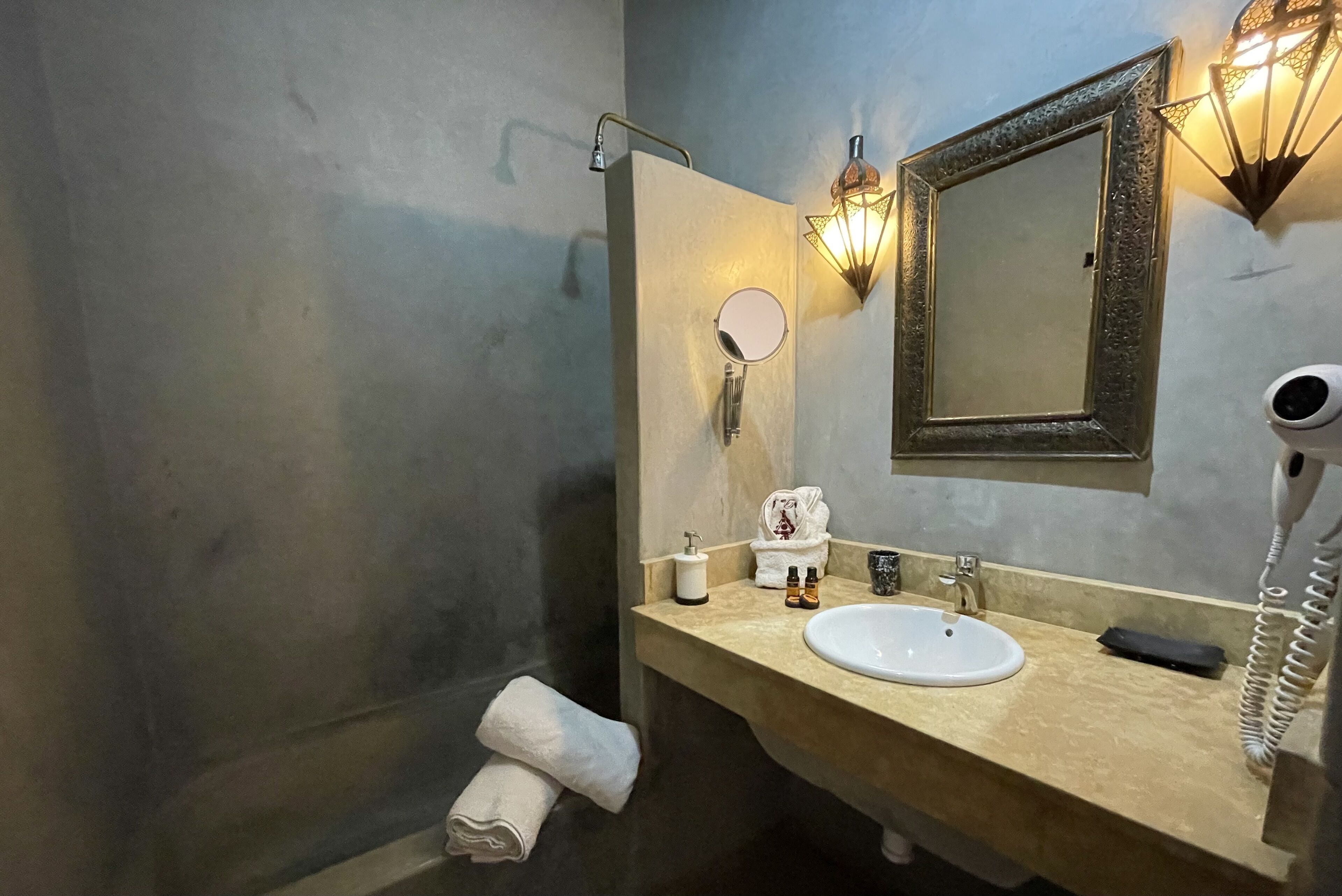 A bathroom with a sink, mirror, towel, and a hairdryer.