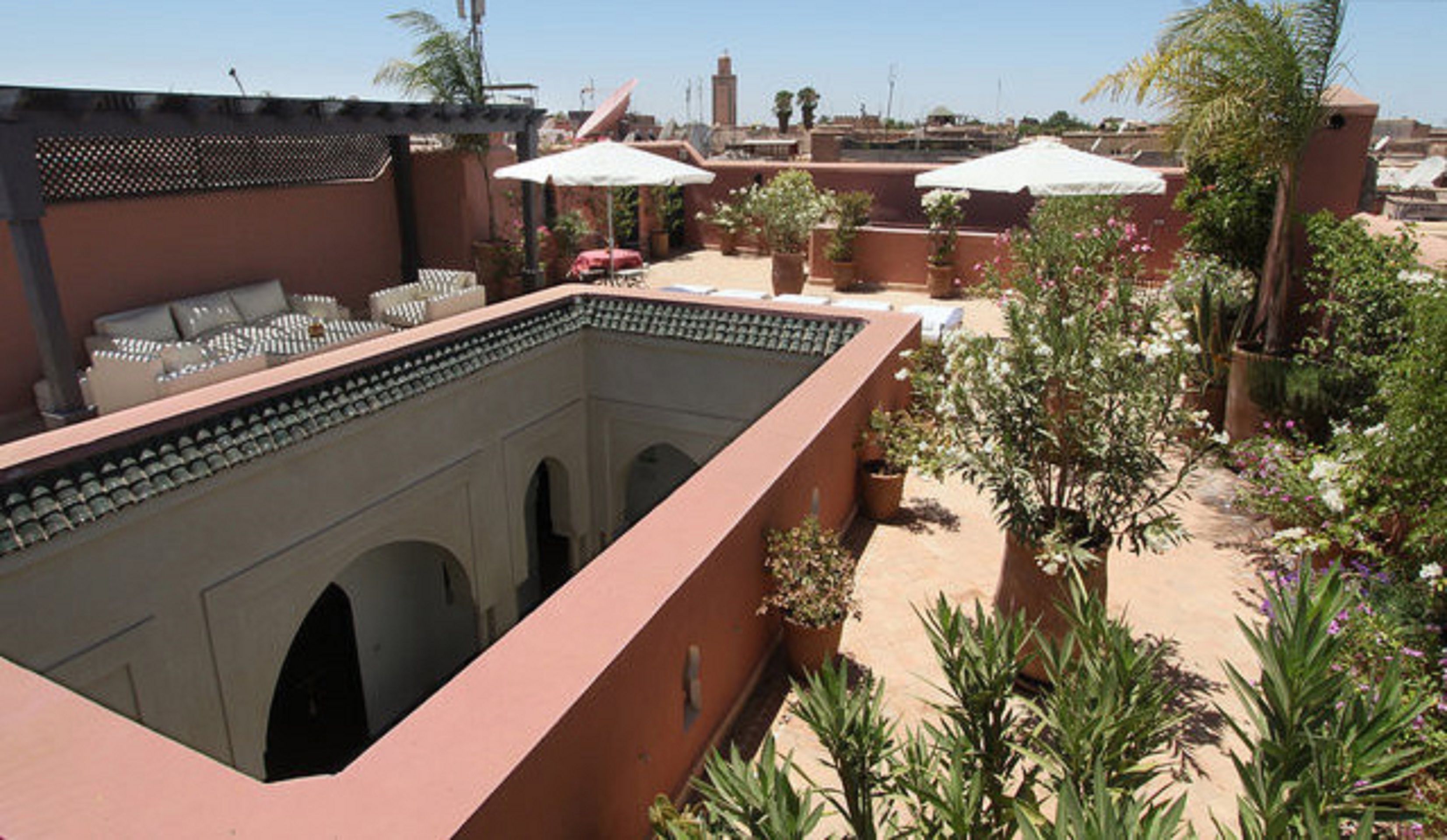 Una terraza en la azotea con piscina, mobiliario exterior y plantas en macetas.